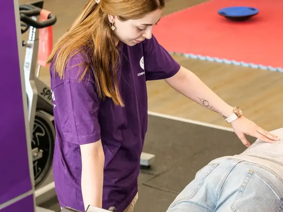 Physiotherapeutin betreut eine Person am Rückenstrecker